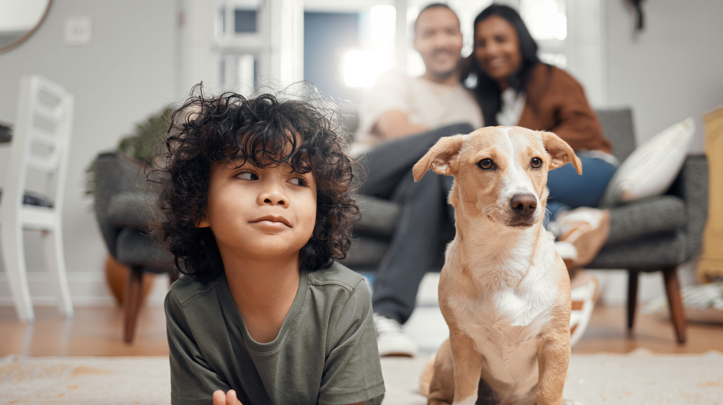 Young kid on floor with small dog, parents looking from behind