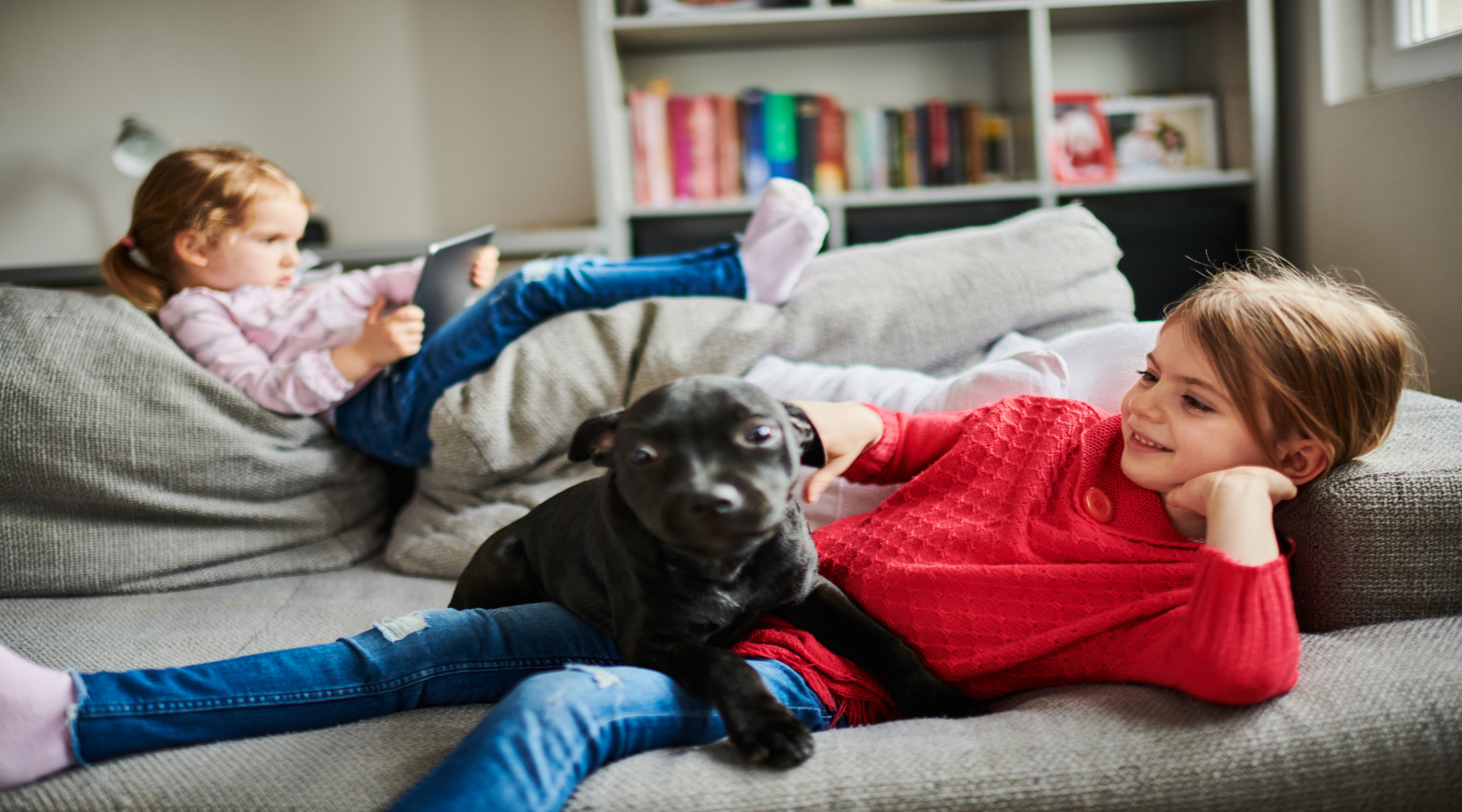 Children and a dog relax on couch